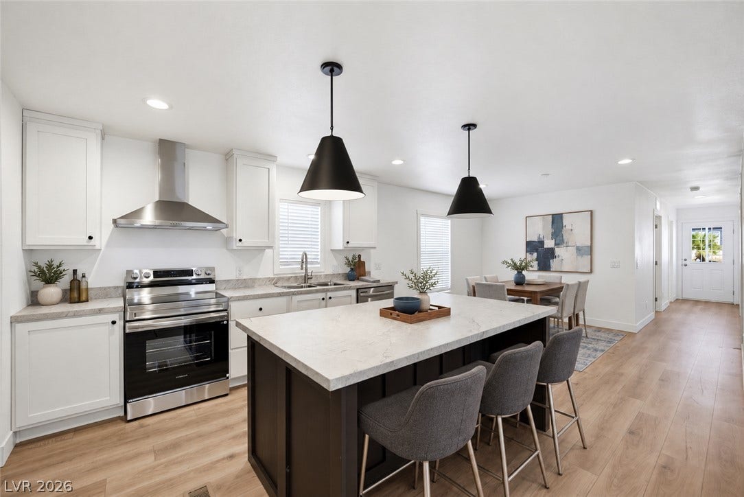 Gleaming wood-style flooring anchors this contemporary kitchen featuring stone counters and a central island.