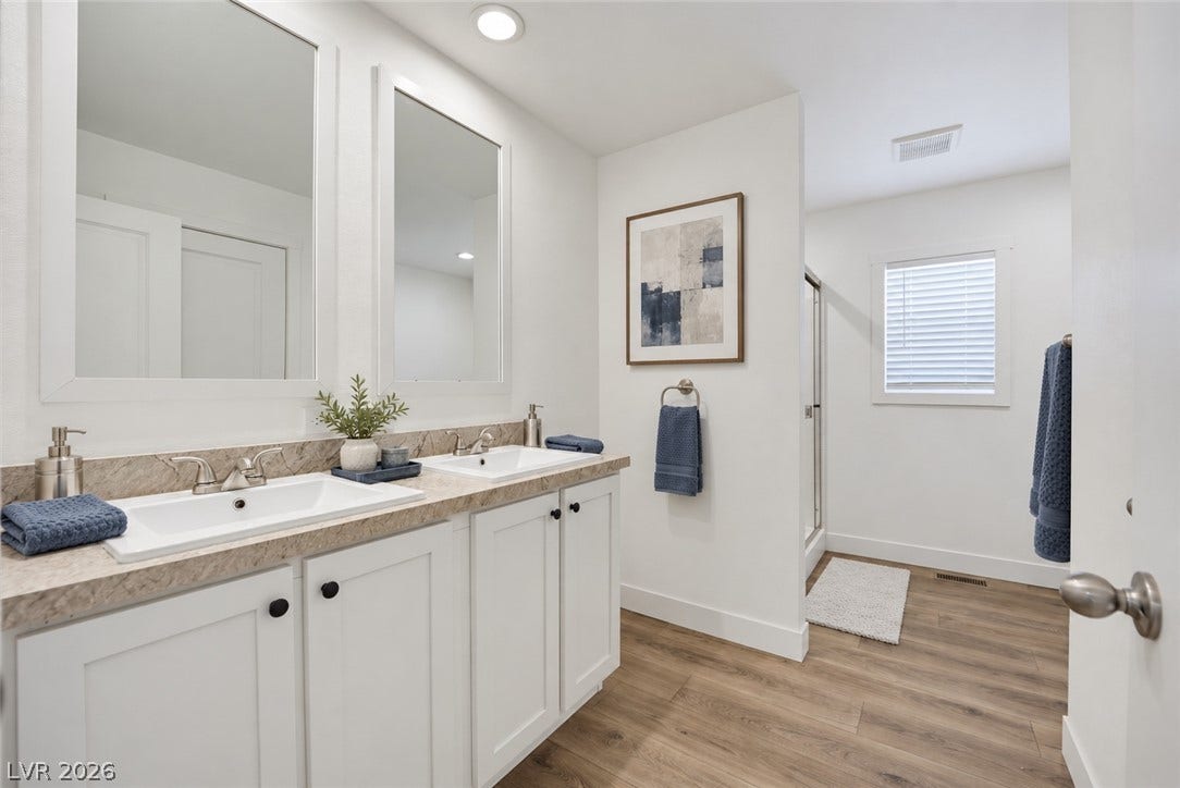 A spacious dual vanity with stone counters anchors this modern master bathroom layout.