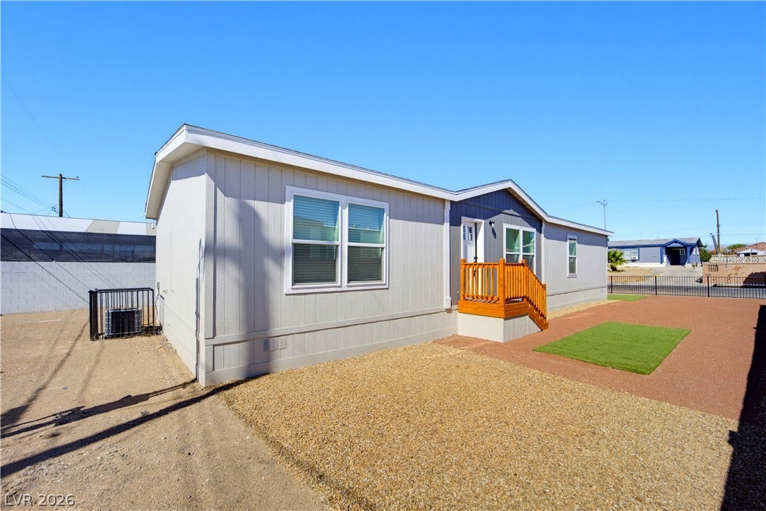 An inviting exterior features clean vertical siding, dual-pane windows, and a raised entry porch.