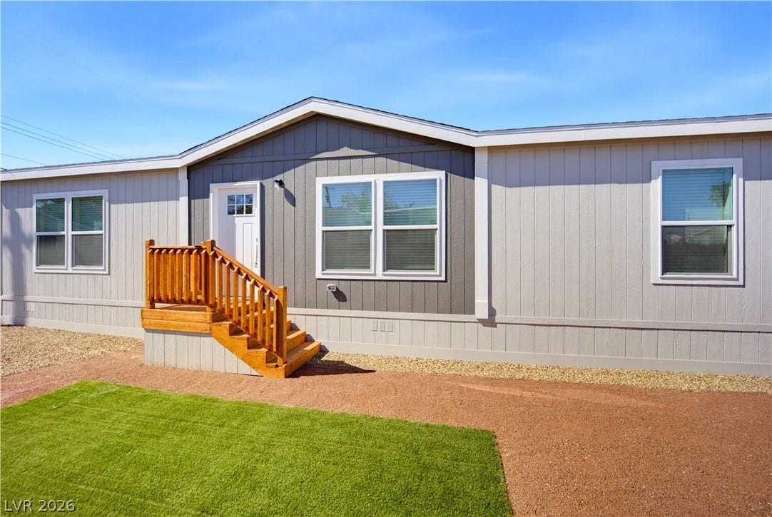 An inviting exterior features a small wooden entry porch and neat vertical siding panels.