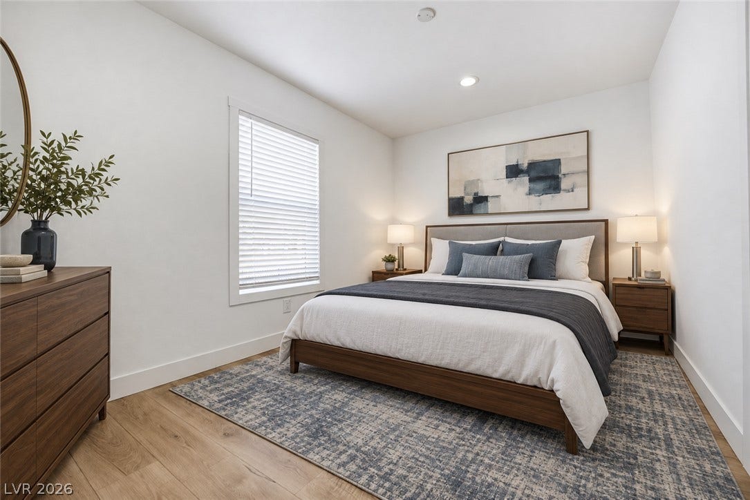 Crisp white walls and warm wood flooring define this inviting bedroom space.