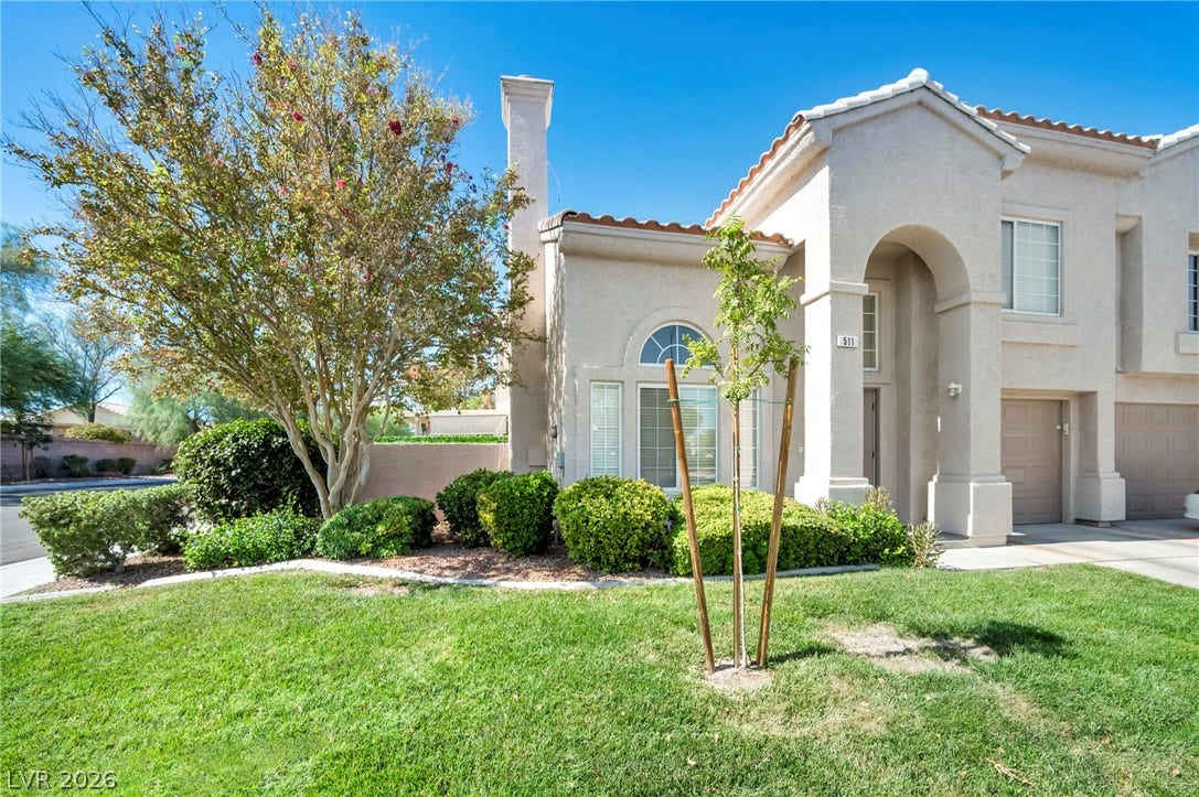 511 Armenian Place, Henderson, NV 89052 Manicured green lawn and mature landscaping frame this elegant stucco exterior with classic arched entry.