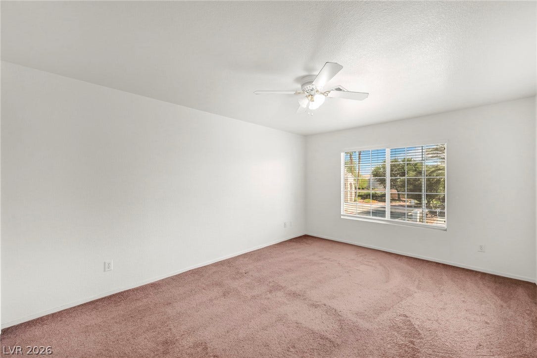 511 Armenian Place, Henderson, NV 89052 A spacious bedroom offers plush carpeting and a large window looking out to the neighborhood.