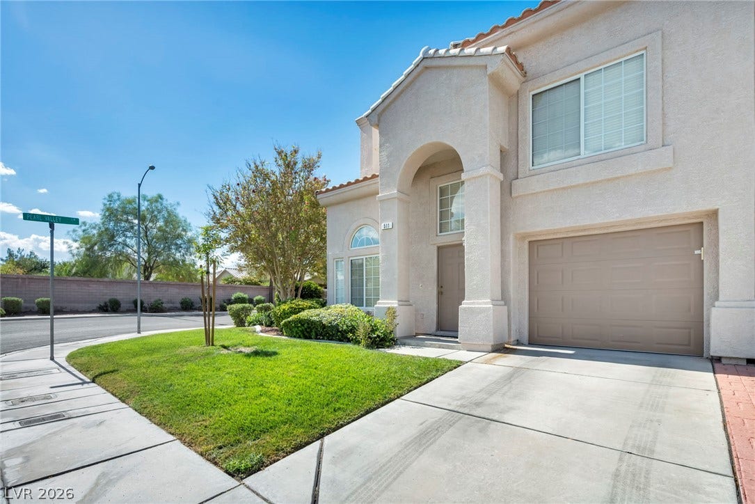 511 Armenian Place, Henderson, NV 89052 An arched entry and a concrete driveway define this stucco home exterior.