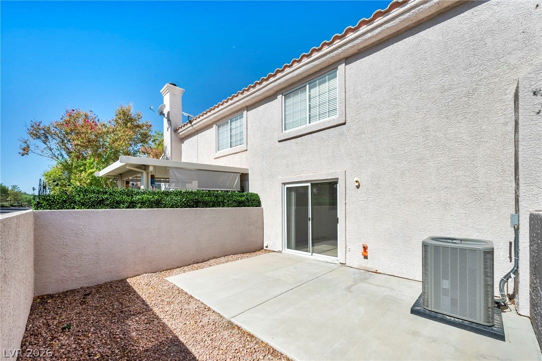 511 Armenian Place, Henderson, NV 89052 A private concrete patio sits enclosed by stucco walls beneath a clear blue sky.