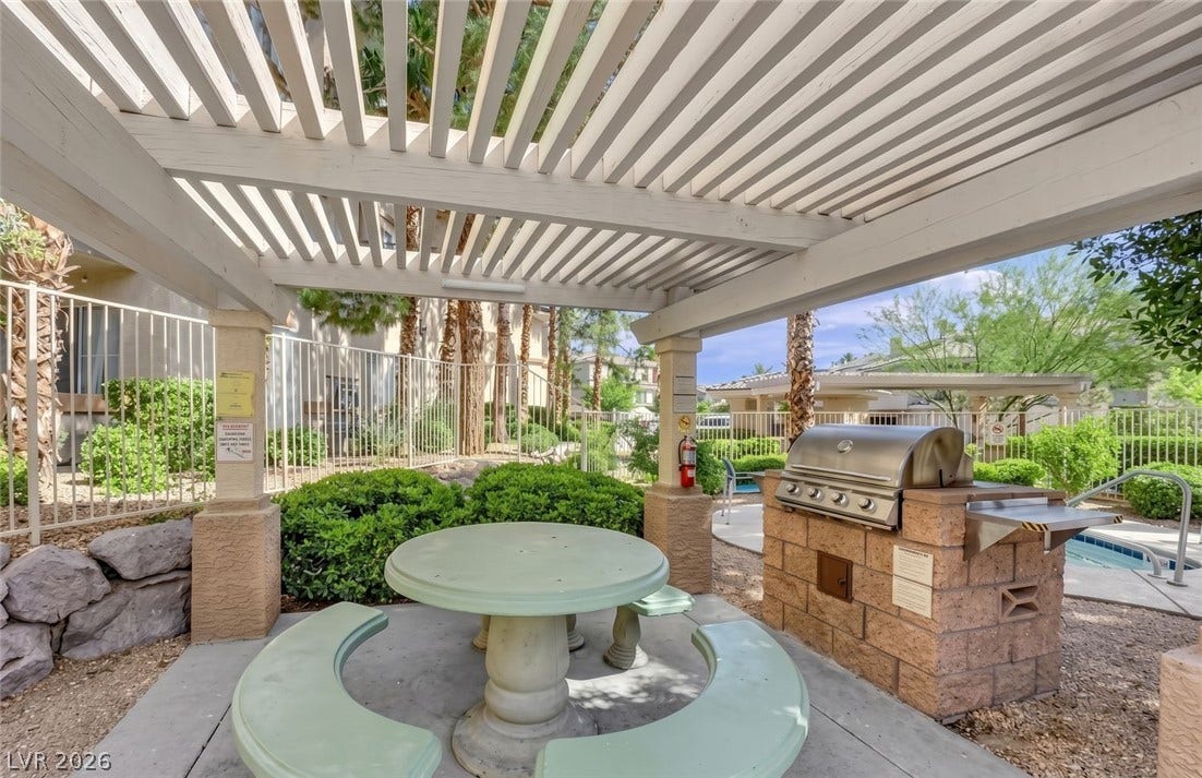 7173 S Durango Drive, #212, Las Vegas, NV 89113 An inviting outdoor kitchen and dining area sits comfortably sheltered beneath a classic white pergola.
