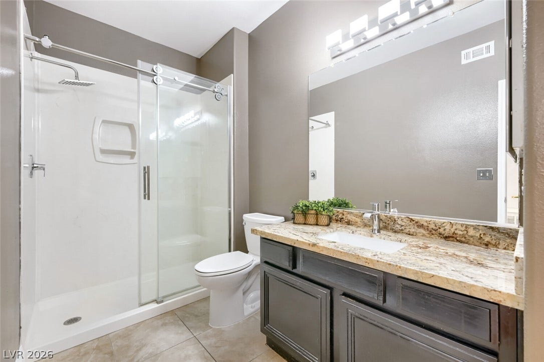 7173 S Durango Drive, #212, Las Vegas, NV 89113 A stone vanity top paired with dark cabinetry elevates this modern bathroom layout.