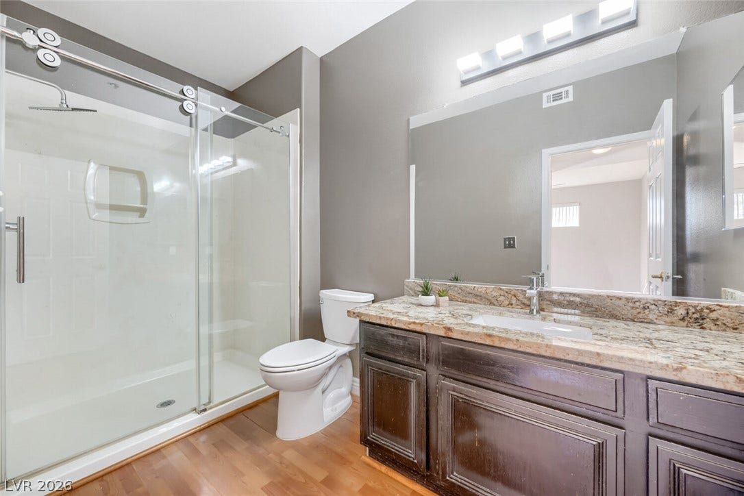 7173 S Durango Drive, #212, Las Vegas, NV 89113 Gleaming stone countertops and a modern glass shower elevate this refined bathroom space.