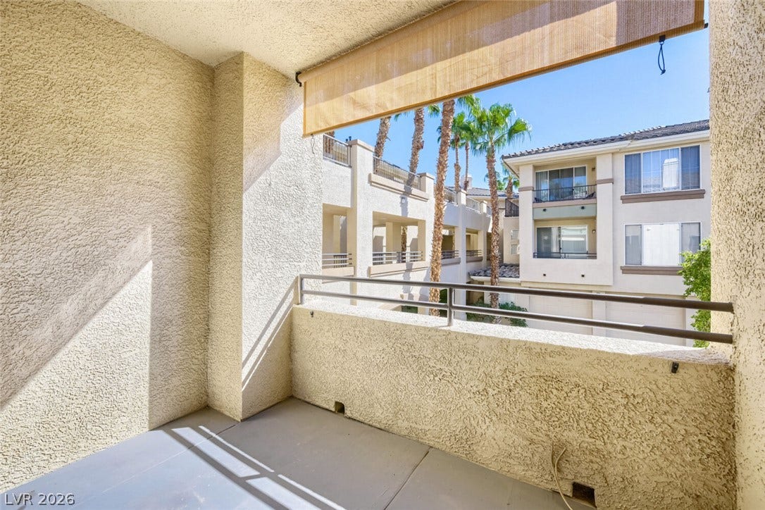 7173 S Durango Drive, #212, Las Vegas, NV 89113 An elevated private balcony looks out over the surrounding neighborhood and mature palm trees.