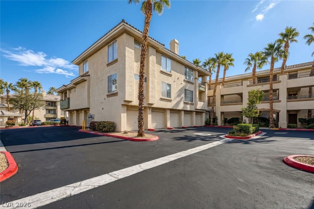 7173 S Durango Drive, #212, Las Vegas, NV 89113 Stucco exterior siding and tile roofs define this multi-level residential building flanked by palm trees.