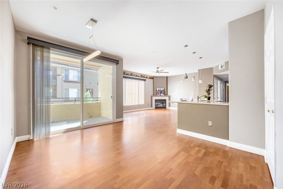 7173 S Durango Drive, #212, Las Vegas, NV 89113 Warm wood flooring and sliding glass doors highlight this inviting open floorplan.