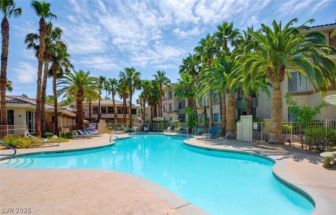 7173 S Durango Drive, #212, Las Vegas, NV 89113 Lush palm trees surround a sparkling blue swimming pool lined with a spacious concrete deck.