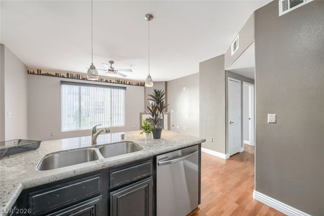 7173 S Durango Drive, #212, Las Vegas, NV 89113 Gleaming stone countertops and warm wood floors define this open kitchen design.