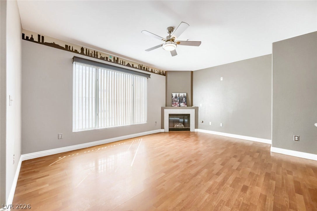7173 S Durango Drive, #212, Las Vegas, NV 89113 Sunlight streams across rich wood flooring in a relaxed living room with a corner fireplace.