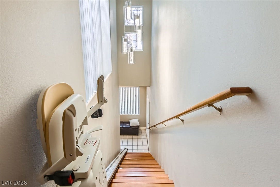 7173 S Durango Drive, #212, Las Vegas, NV 89113 High ceilings and tall windows frame the hardwood staircase equipped with a convenient motorized lift.
