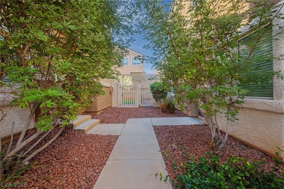 1555 Ward Frontier Lane, Henderson, NV 89002 Mature green plantings border a neat concrete walkway leading to a gated entry.
