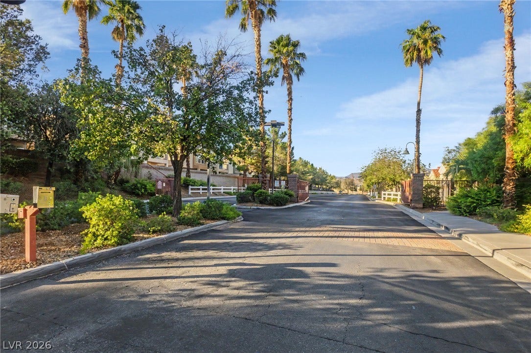 1555 Ward Frontier Lane, Henderson, NV 89002 Towering palm trees frame the gated community entrance lined with paved roads and sidewalks.