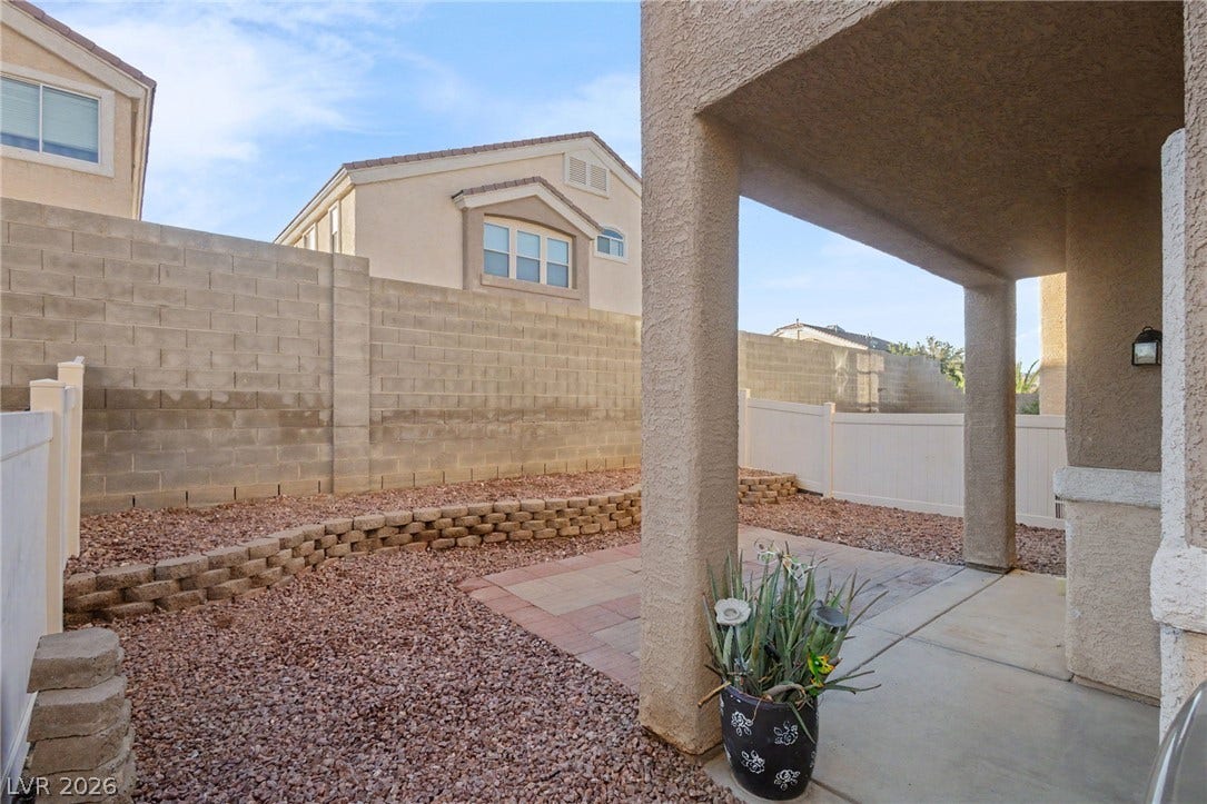 1555 Ward Frontier Lane, Henderson, NV 89002 An enclosed backyard patio features low-maintenance gravel landscaping and a concrete terrace.