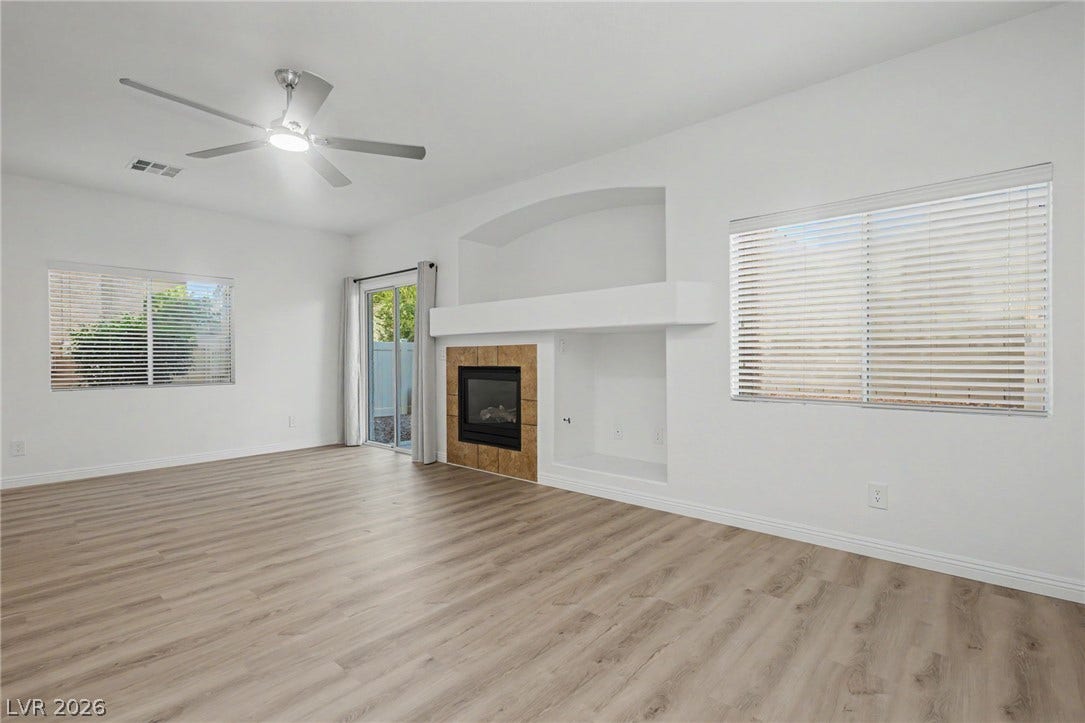 1555 Ward Frontier Lane, Henderson, NV 89002 Smooth wood floors anchor this open space featuring a tiled fireplace and sliding glass doors.