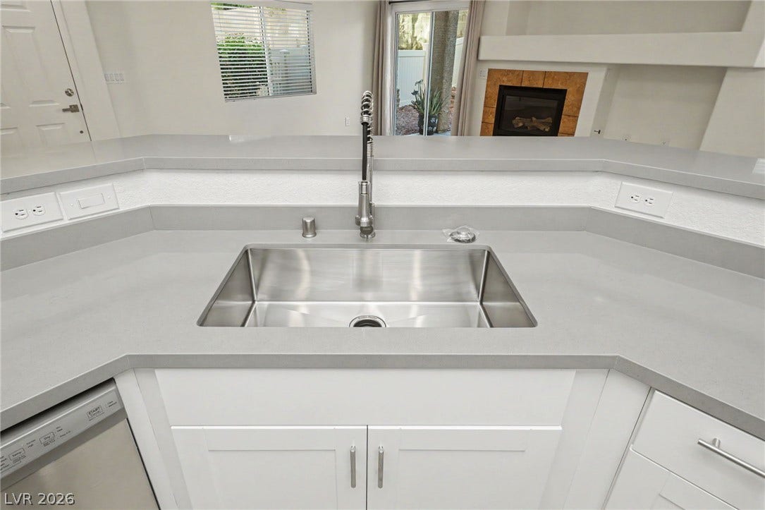 1555 Ward Frontier Lane, Henderson, NV 89002 An open kitchen layout features a large under-mount stainless steel sink and stone counters.