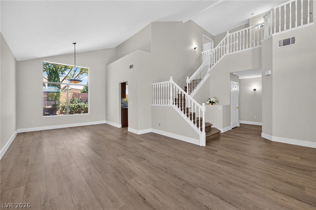 Newly Renovated Interior: Featuring two-story soaring ceilings @ Foyer, Living & Dining Rooms, with wood-look Luxury Vinyl Plank flooring, complemented by a grand staircase leading to the upper level.