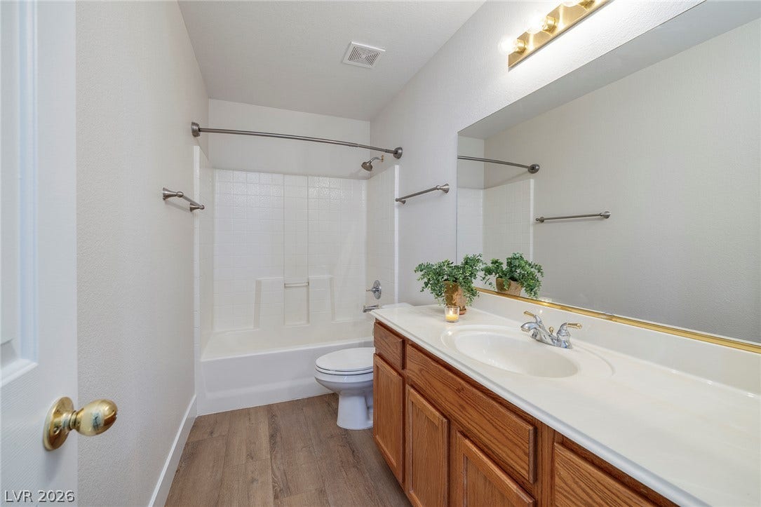 A downstairs full bathroom features a tub/shower and a long vanity with ample storage and counter space along with a full-sized mirror.