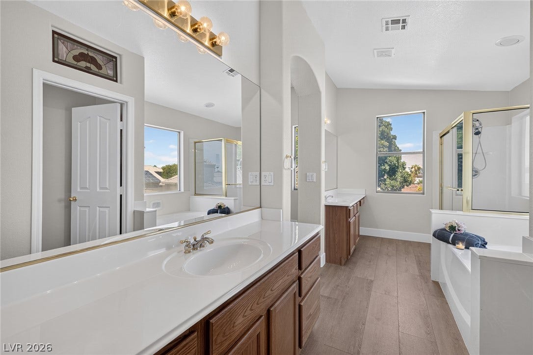 Dual vanities and a deep soaking tub with separate shower create a luxurious primary bathroom oasis with plenty of room for two.