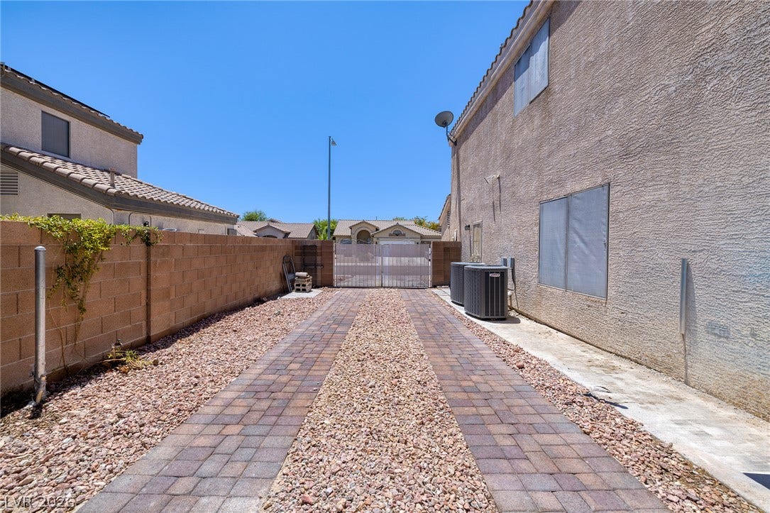 A long paved driveway leads to Gated RV Parking with paver treads and a gravel center.
