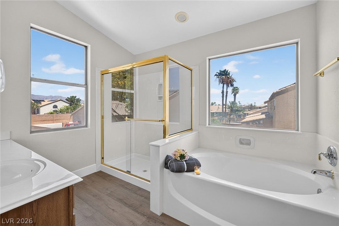 A tranquil primary bathroom features a luxurious soaking tub, a separate shower, and generous eastern natural light.
