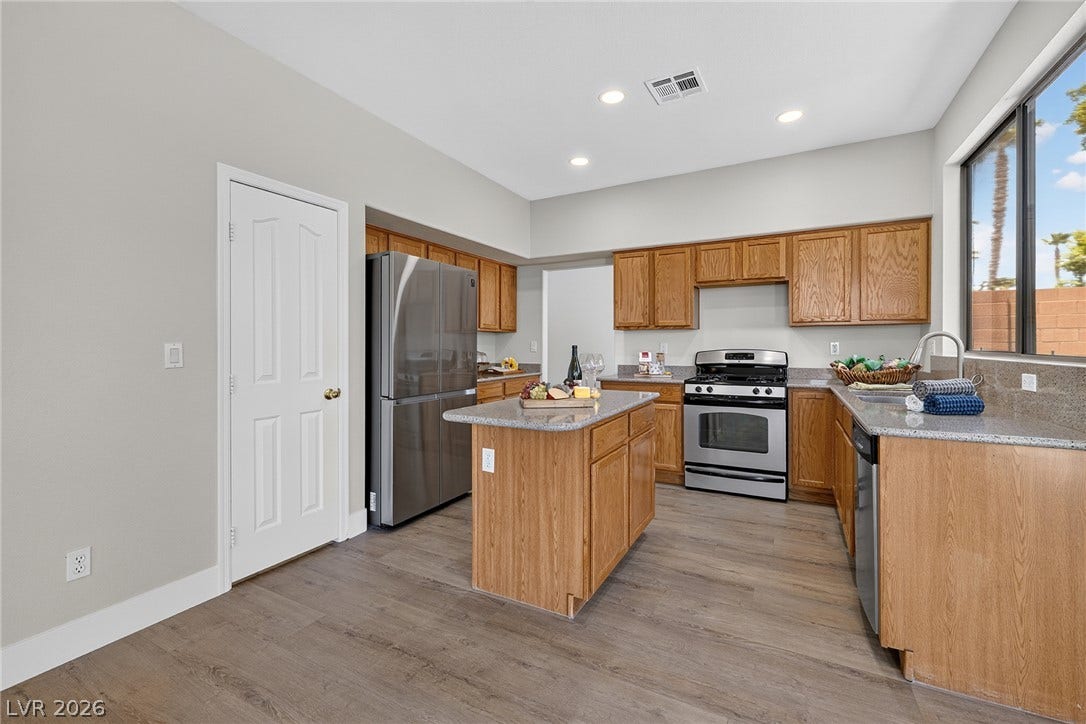 Kitchen features newly installed recessed lighting, stainless steel appliances, abundant cabinetry, a walk-in pantry and a central island with Silestone counters.