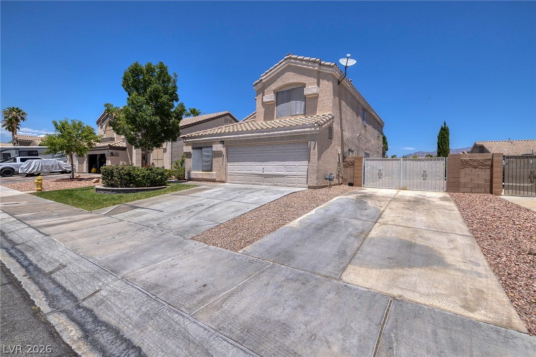 A classic two-story stucco home with a double garage and ample concrete driveway leading to Gated RV Parking,