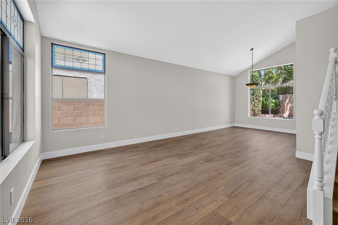 Natural light illuminates this spacious living area, featuring vaulted ceilings and rich LVP flooring.