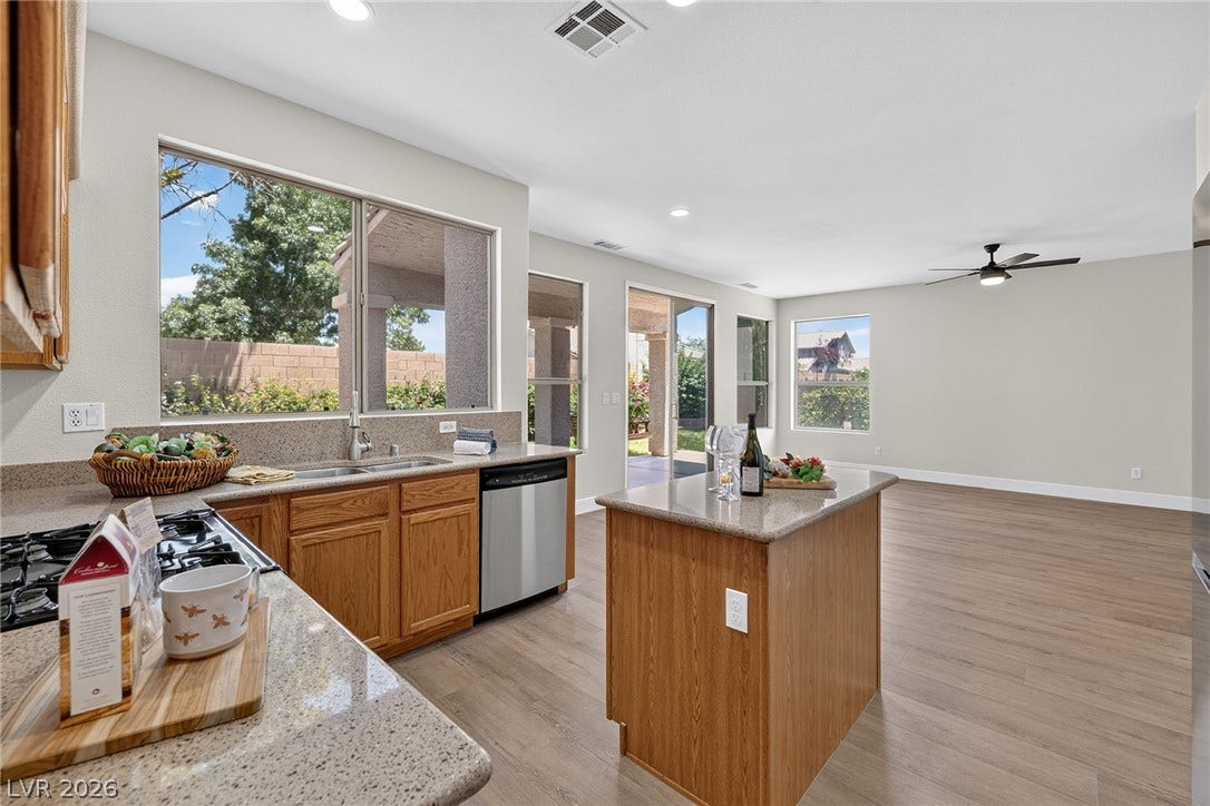 A well-lit kitchen with natural light and ample Silestone counter space, flowing into an open Family Room.