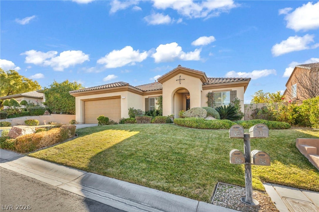 37 Stonemark Drive, Henderson, NV 89052 Mediterranean / spanish house with a front yard, an attached garage, a tile roof, concrete driveway, and stucco siding