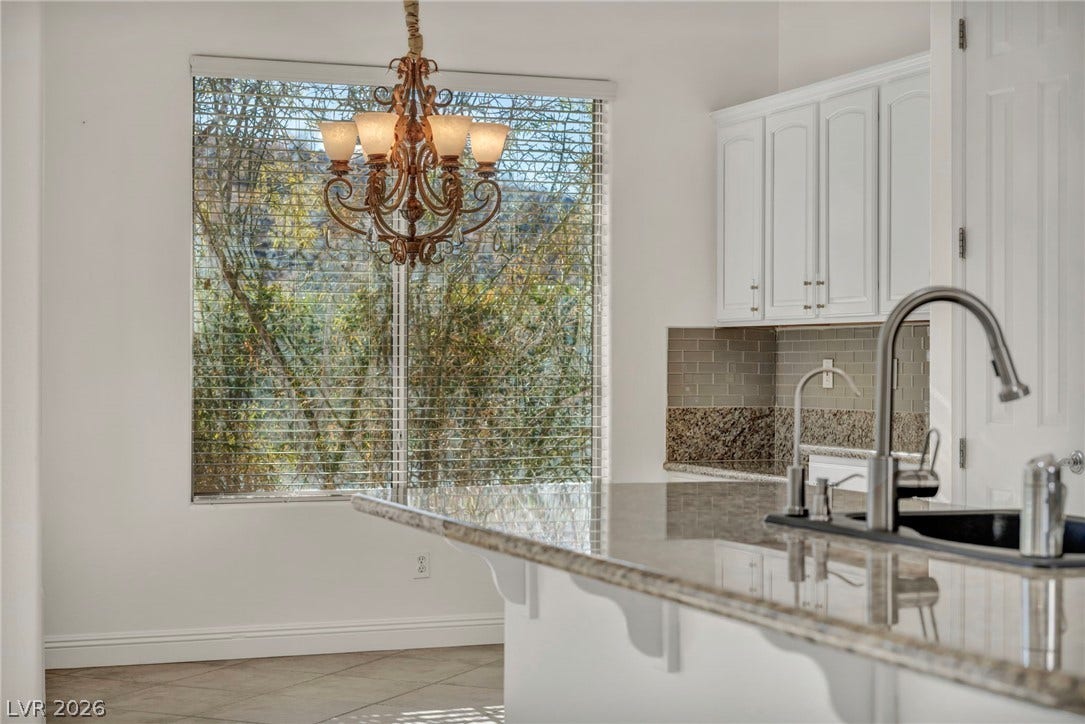 37 Stonemark Drive, Henderson, NV 89052 Kitchen featuring white cabinets, baseboards, a notable chandelier, and light stone countertops