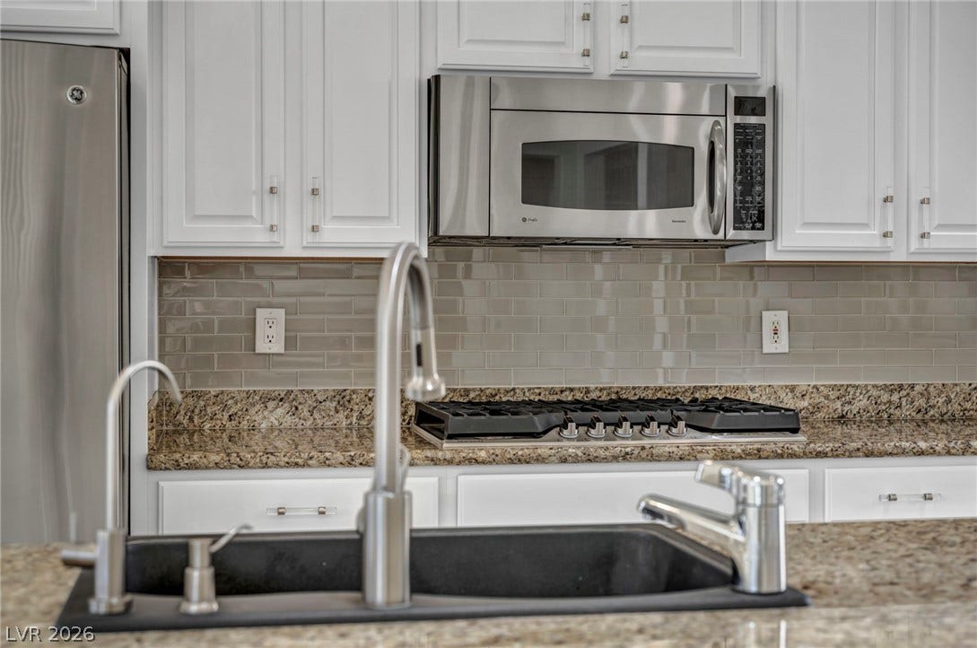 37 Stonemark Drive, Henderson, NV 89052 Kitchen with tasteful backsplash, white cabinetry, light stone countertops, and stainless steel appliances