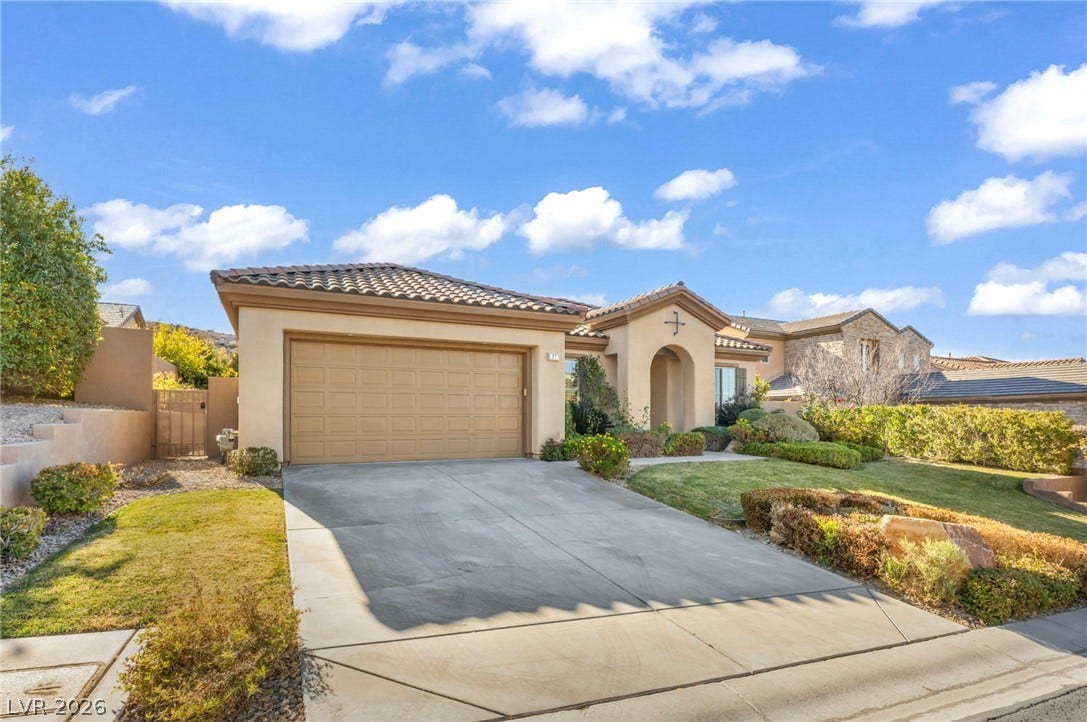 37 Stonemark Drive, Henderson, NV 89052 Mediterranean / spanish-style house with stucco siding, driveway, an attached garage, a front lawn, and a tile roof