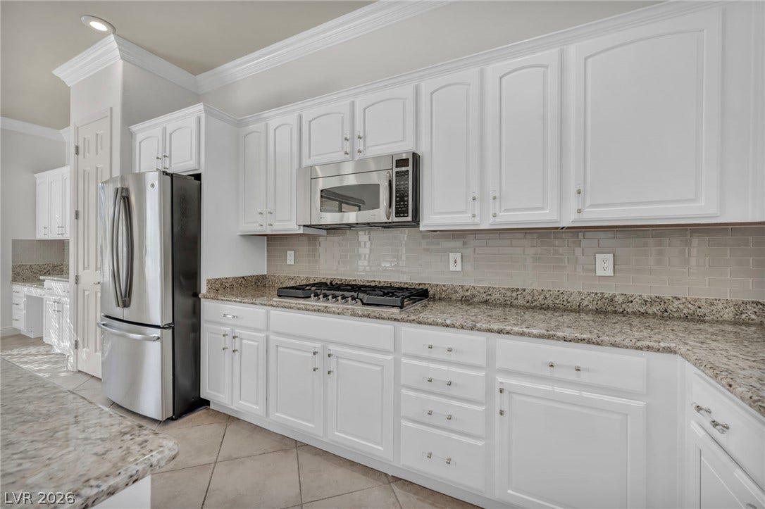 37 Stonemark Drive, Henderson, NV 89052 Kitchen featuring ornamental molding, white cabinets, light tile patterned flooring, stainless steel appliances, and decorative backsplash