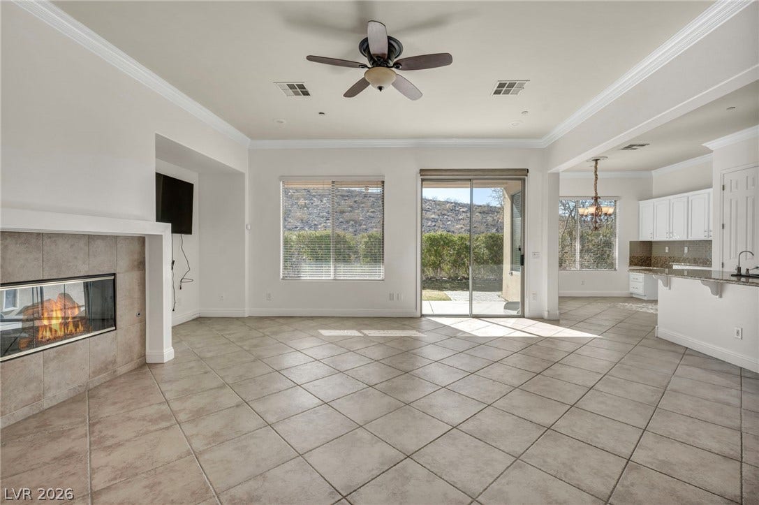 37 Stonemark Drive, Henderson, NV 89052 Unfurnished living room with visible vents, a tile fireplace, light tile patterned floors, and ceiling fan with notable chandelier