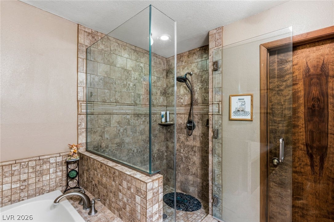 29 Cottonwood Drive, Blue Diamond, NV 89004 Tiled walls and glass panels elevate this modern walk-in shower and tub surround.