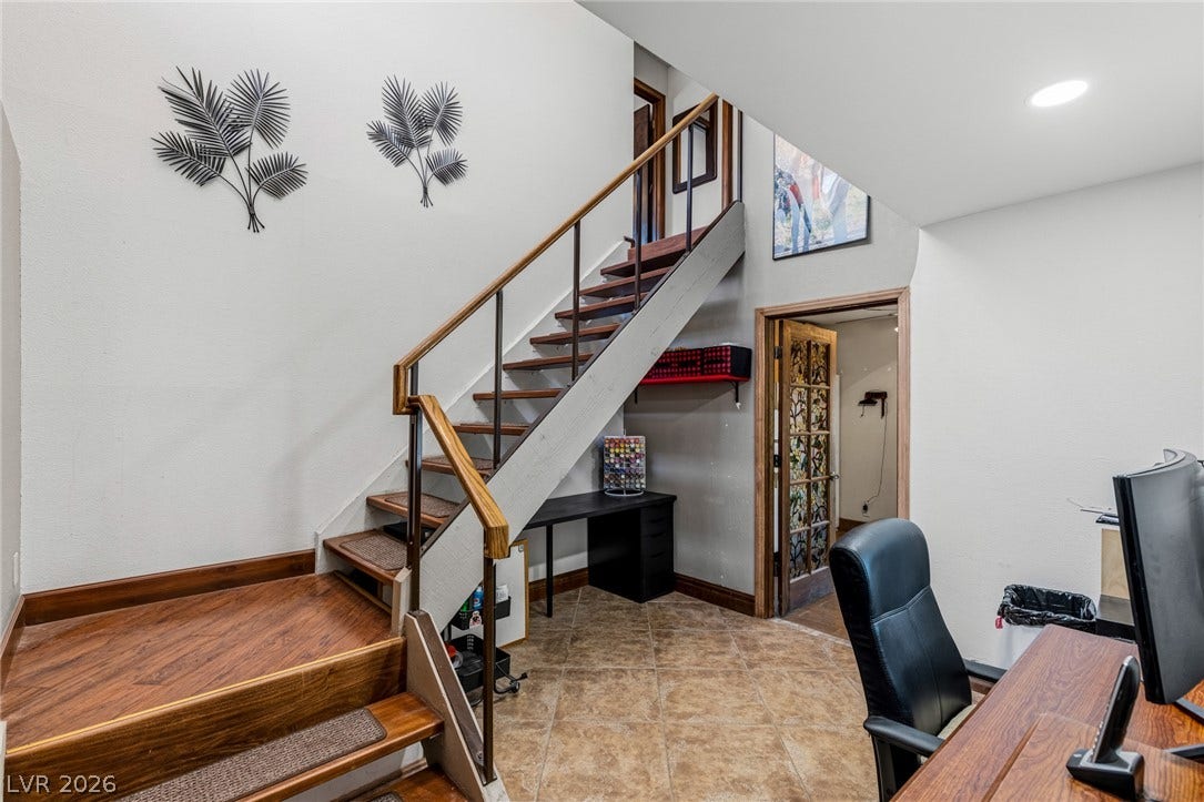29 Cottonwood Drive, Blue Diamond, NV 89004 An open staircase transitions between different levels near the home office workspace.