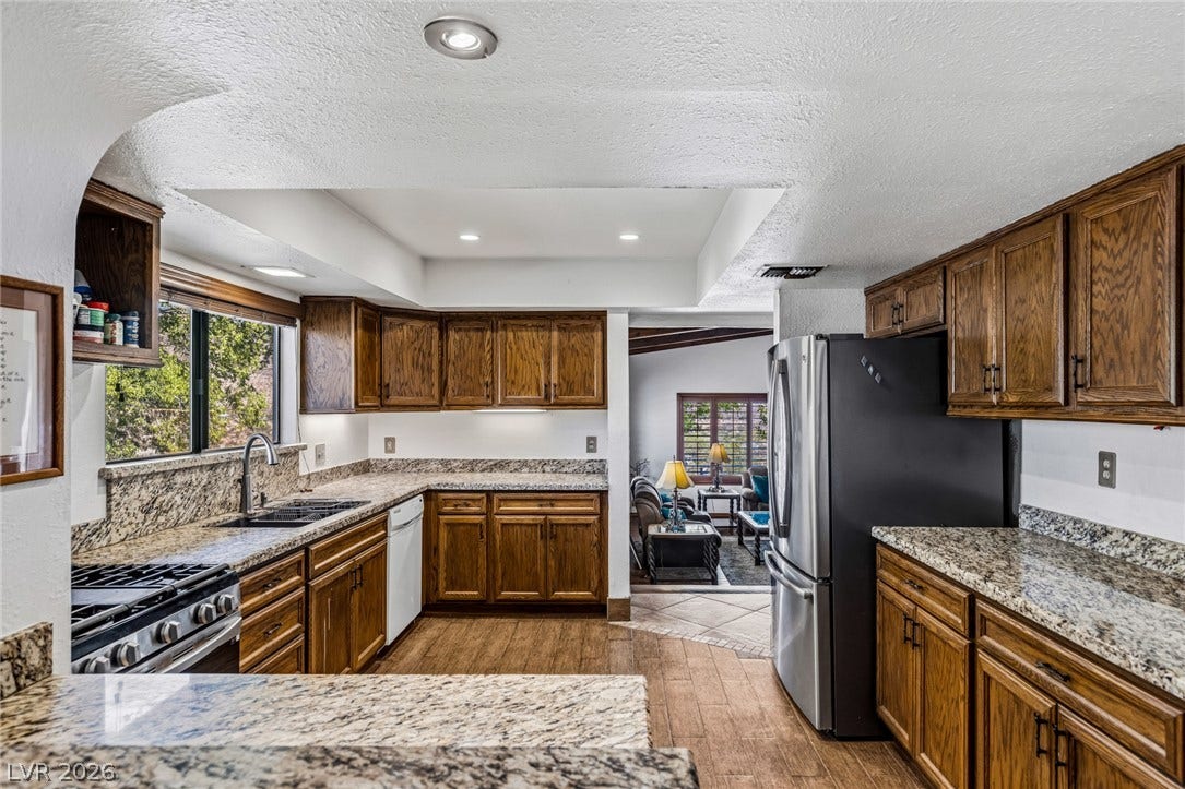 29 Cottonwood Drive, Blue Diamond, NV 89004 Rich wood cabinetry paired with granite stone countertops defines this functional kitchen workspace.