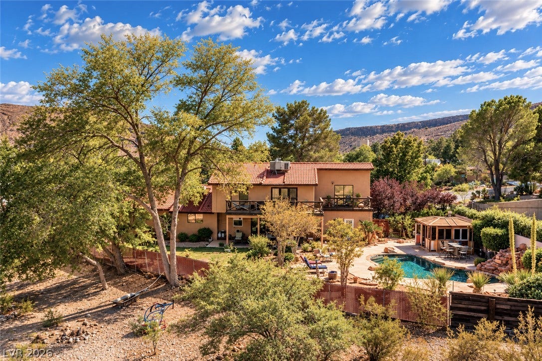 29 Cottonwood Drive, Blue Diamond, NV 89004 Mature trees surround a multi-level desert home featuring a tiled roof and backyard swimming pool.