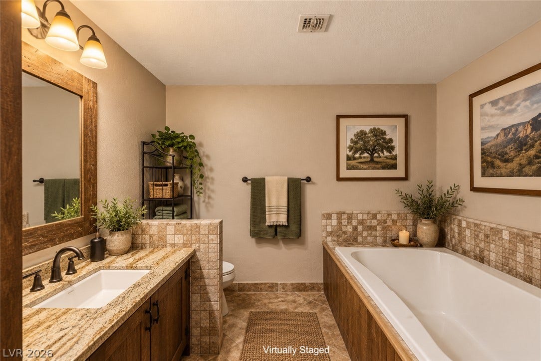 29 Cottonwood Drive, Blue Diamond, NV 89004 A deep soaking tub sits adjacent to a granite-topped vanity in this tiled bathroom.