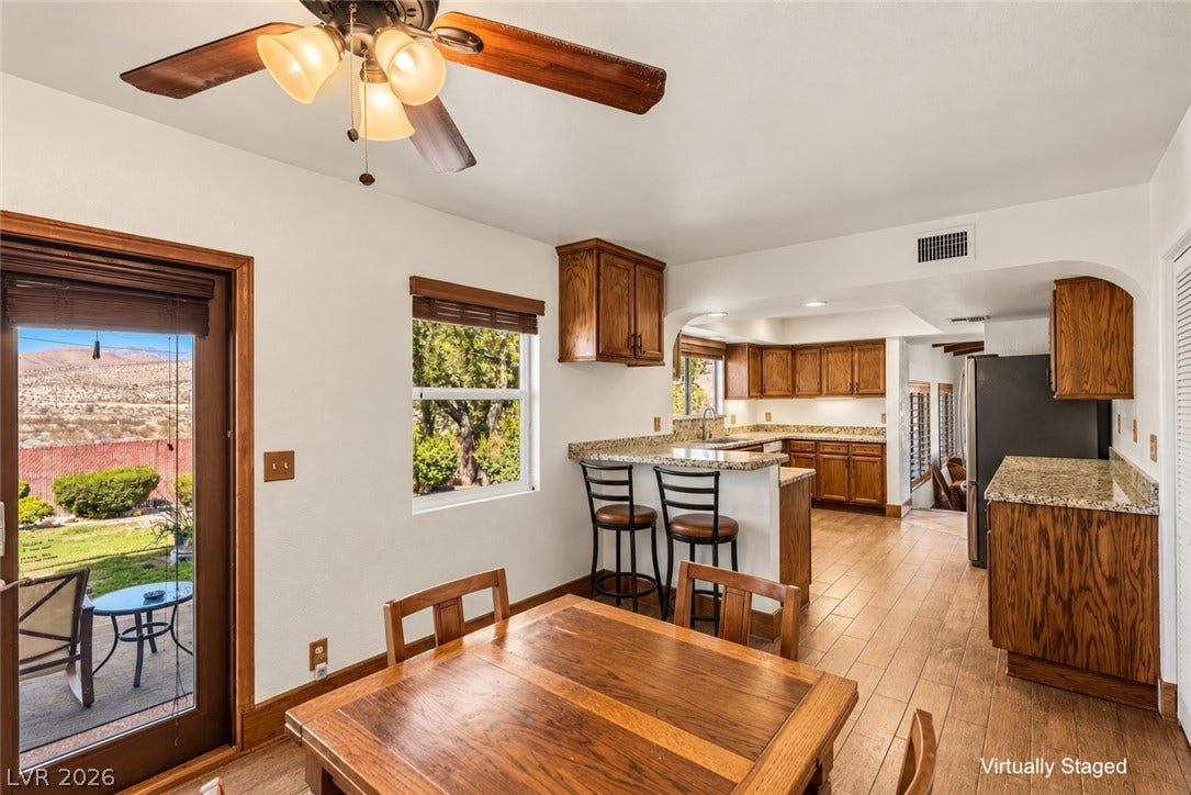 29 Cottonwood Drive, Blue Diamond, NV 89004 Rich wood cabinetry and stone countertops accent this light-filled dining space and open kitchen layout.