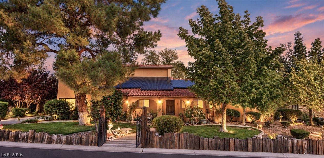 29 Cottonwood Drive, Blue Diamond, NV 89004 Mature trees frame the architectural lines of this multi-level home under a twilight sky.