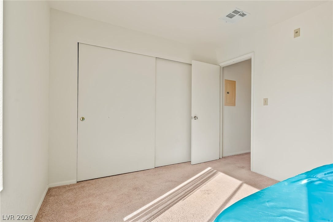2036 Mesquite Lane, #303, Laughlin, NV 89029 Sunlight streams across the carpeted floor of this simple bedroom with sliding closet doors.