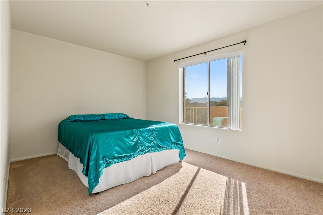 2036 Mesquite Lane, #303, Laughlin, NV 89029 Natural light streams through a large window overlooking scenic neighborhood views in this carpeted bedroom.