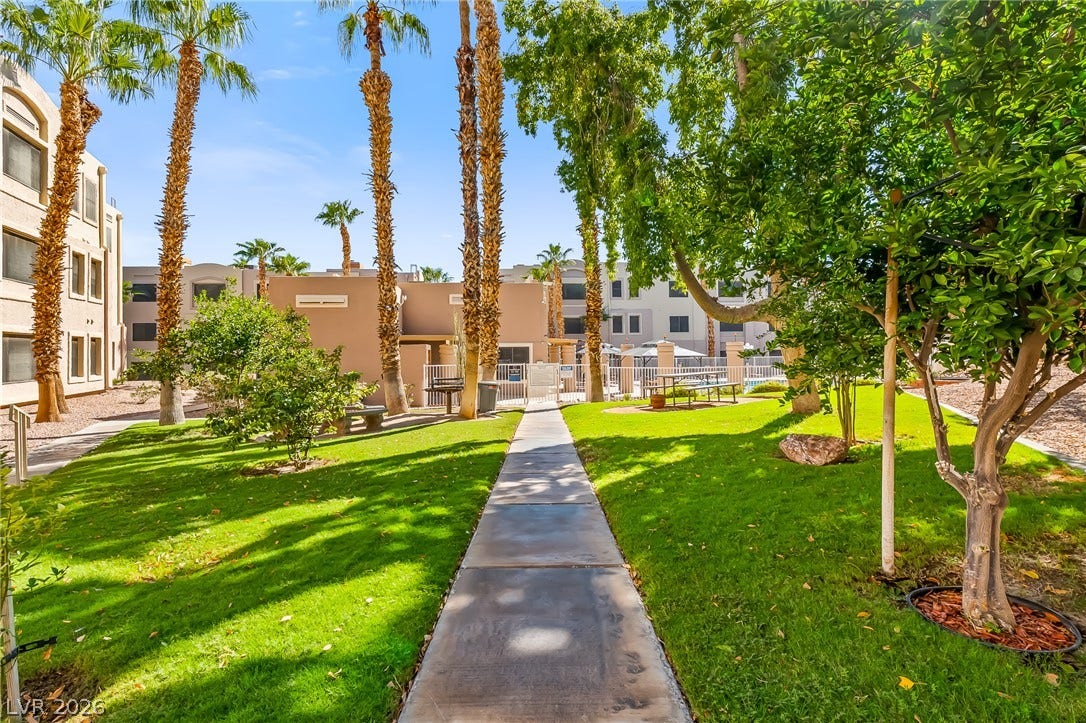 2036 Mesquite Lane, #303, Laughlin, NV 89029 Manicured green lawns and towering palm trees frame a paved pathway through the community grounds.