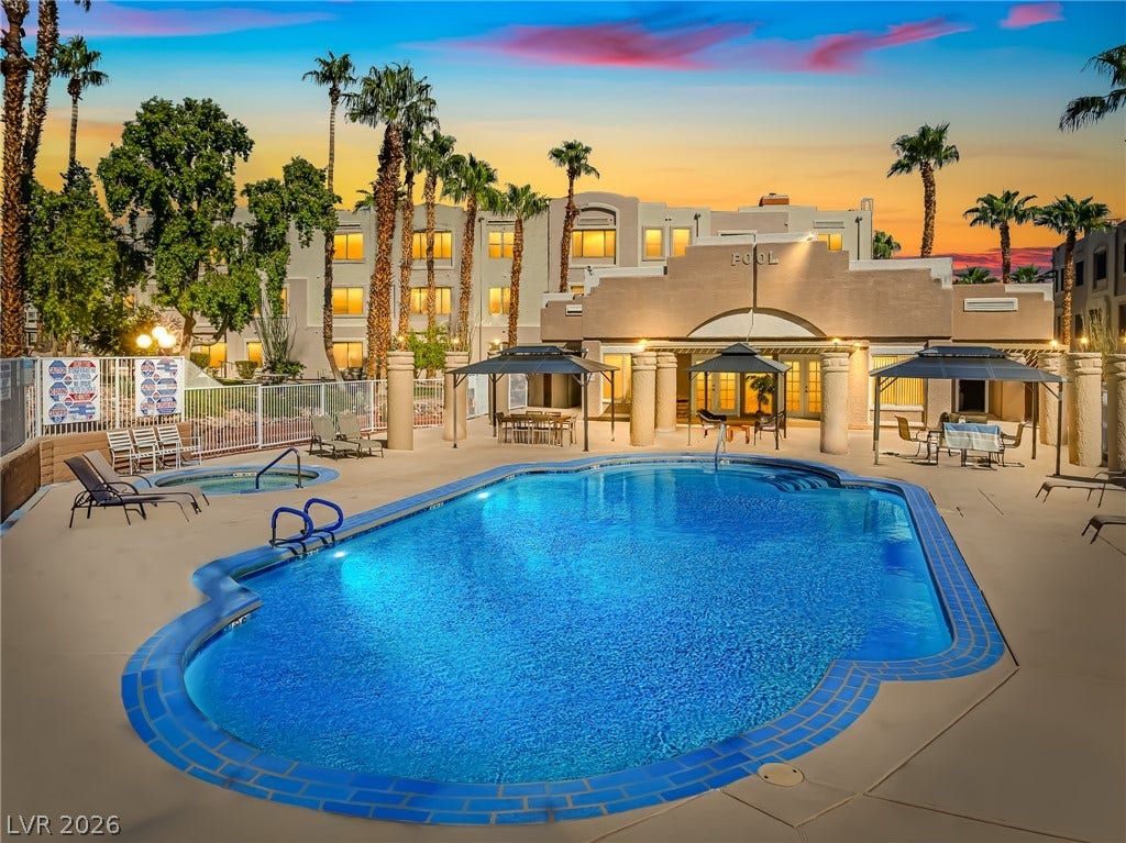 2036 Mesquite Lane, #303, Laughlin, NV 89029 Lush palm trees surround a sparkling blue swimming pool and spa area at twilight.